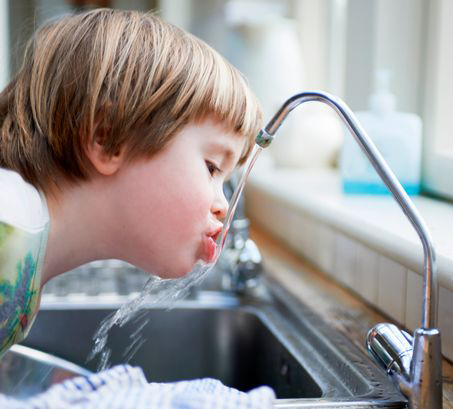 young boy drinking tap water
