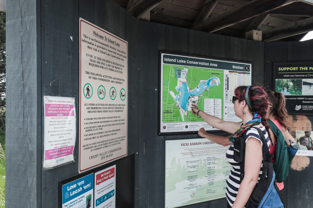 Park visitor pointing to a map of Island Lake at a park kiosk.
