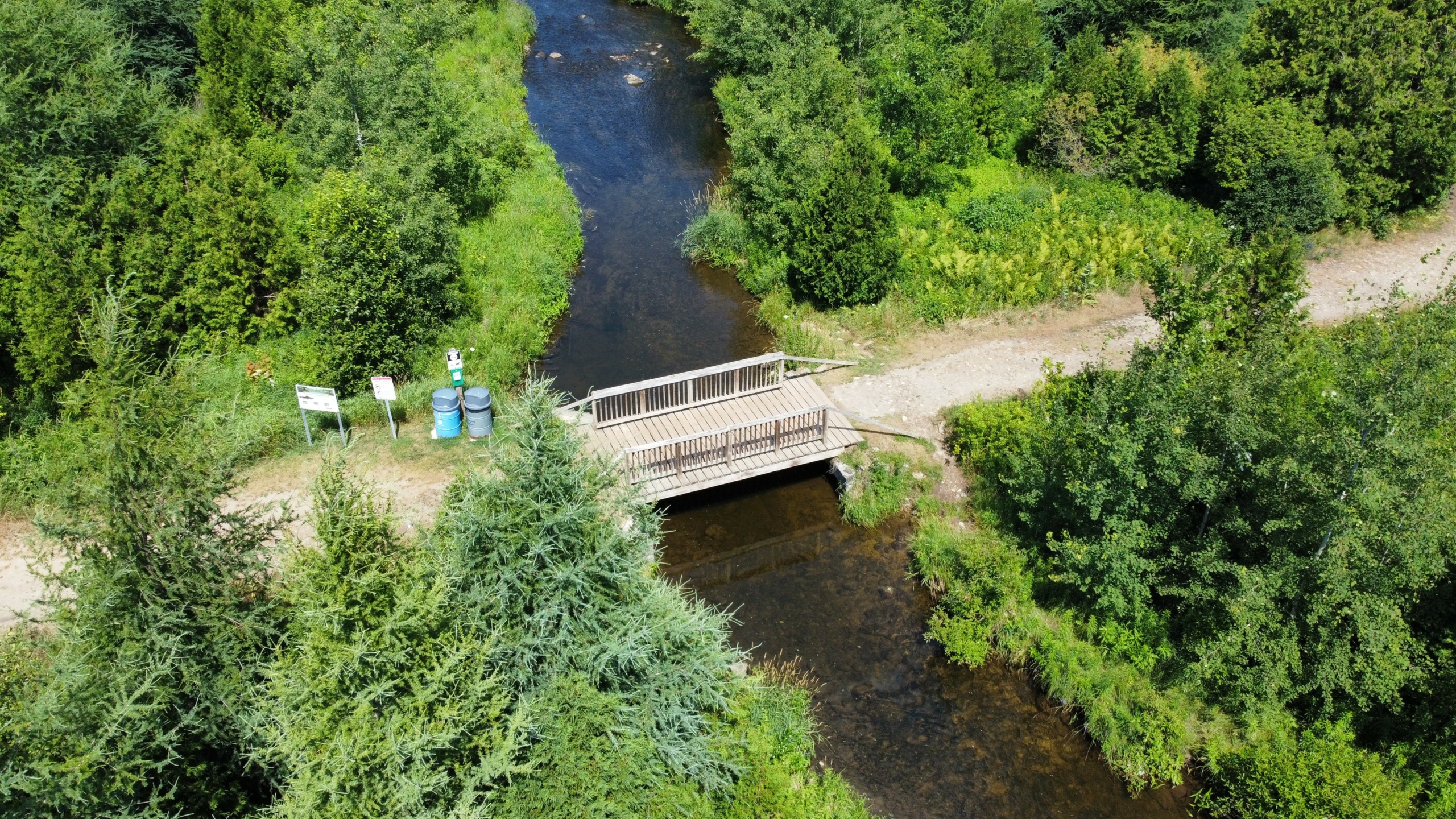 Aerial view of a wooden bridge over a river surrounded by forest.